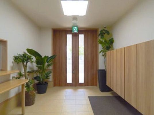 エントランスには大きな靴箱があり、複数の観葉植物が飾られている。靴箱の向かいには受付もある。