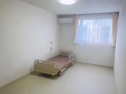 エアコンが付いた部屋には介護ベッドが置かれている。ベッドサイドには緊急通報装置もある。