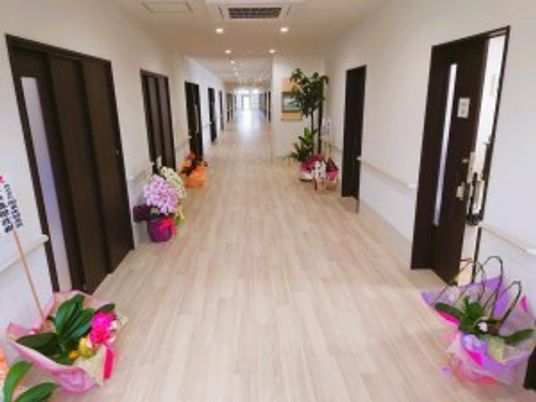 幅の広いまっすぐな廊下は両サイドに手すりが設置され、お祝いの花や観葉植物が飾られている。