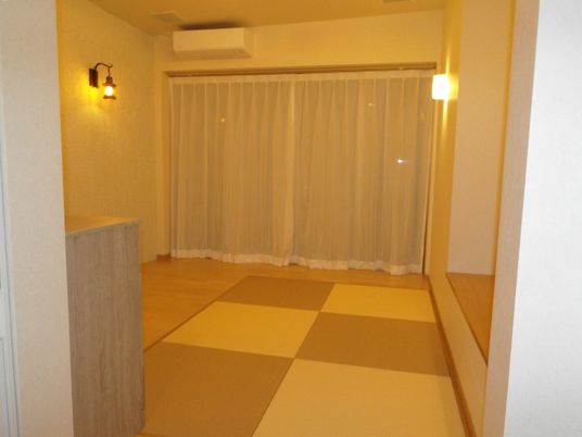 淵のない正方形の畳が並べられている部屋の様子。奥のほうにエアコン、手前にタンス類