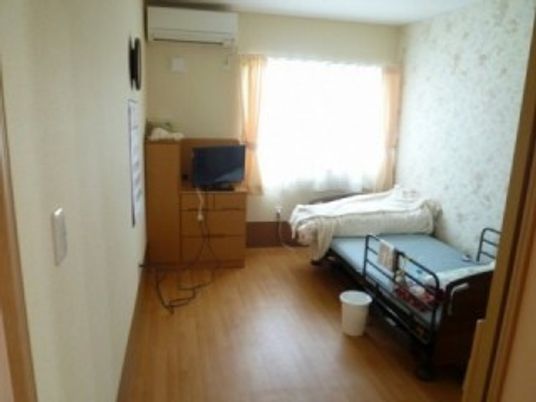 大きな窓が付いたフローリングの部屋には大きなベッドがあり、寝具がセットされている。タンスなどもある。