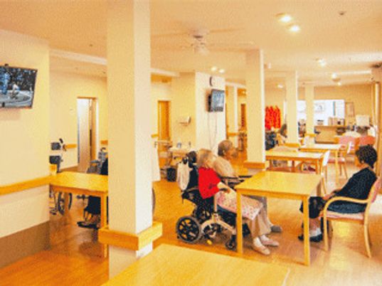 ダイニングテーブルが複数あり、車いすを利用している人もそうでない人も一緒にテーブルを囲んでいる。