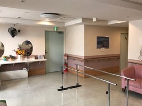 平行棒が設置されたスペースには車いす対応の洗面所やピンクの一人用のソファが置かれている。