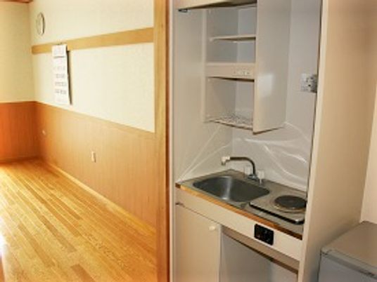 部屋に取り付けられた電子調理器と流し台のミニキッチン