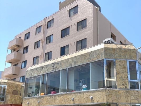 ブラウン系の建物は大きく、建物の一部は大きな窓が付いていて、人の姿が見える。