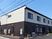 ２階建ての建物は日当たりのいい場所に建っていて、1階部分がダークグレー、2階部分が白い外壁。
