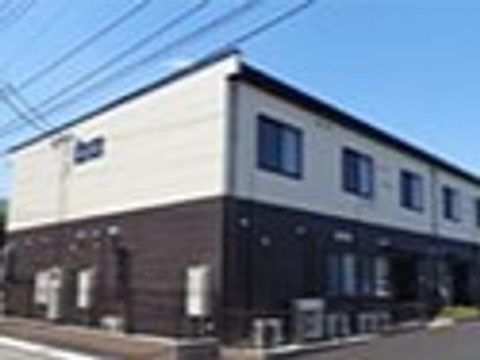 ２階建ての建物は日当たりのいい場所に建っていて、1階部分がダークグレー、2階部分が白い外壁。
