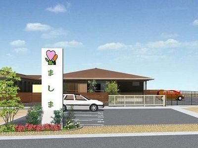 ブラウンを基調とした平屋建ての建物。駐車スペースが広く、日がよく当たる。