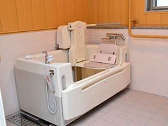 介護仕様の浴槽が置いてある広めの浴室の様子。手すりがついた近代的な浴室