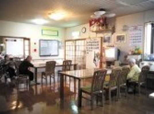 入居者が思い思いの場所で過ごしているリビングは明るい雰囲気で、壁には複数の掲示物が飾られている。