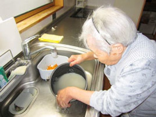 お米を研いでいる高齢者を写した写真。施設内で行われているリハビリの一場面