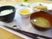 みそ汁に白いご飯、煮物、青菜の和え物などが並んでいるトレーには箸とスプーンがある。