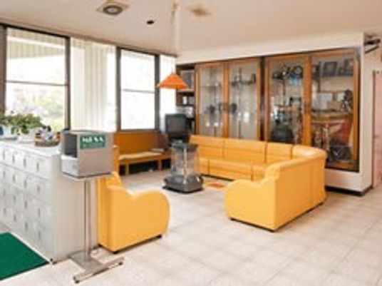 ストーブを囲むようにして置かれた黄色いソファの応接セット。ソファの後ろには大きな飾り棚があり、たくさんの小物が飾られている。