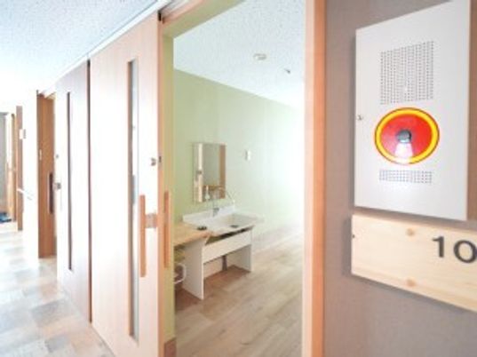 ワイドタイプのスライド式のドアが設置された個室の部屋には車いす対応の洗面所がある。