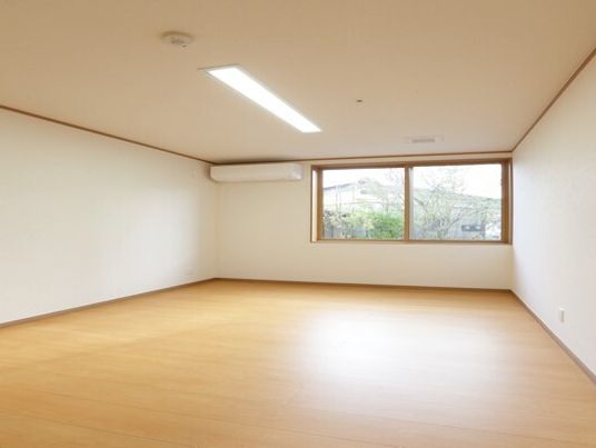 エアコンやスプリンクラー、照明がついたシンプルな個室のお部屋。窓にはカーテンはない。