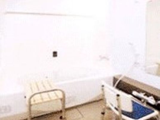 ベンチが設置された白い浴槽の横にはシャワーチェアとシャワーがある。