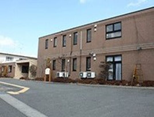 ２階建ての建物はブラウンを基調とし、広い敷地内には駐車スペースもある。