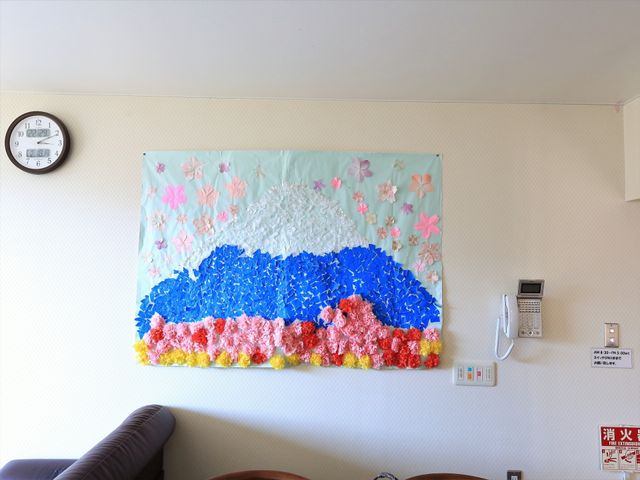 壁掛けアートのある居室 装飾 居室の壁には、色彩豊かなアートが飾られ、温かみのある雰囲気を演出しています。ゆったり過ごせる空間が、そこには広がっています。