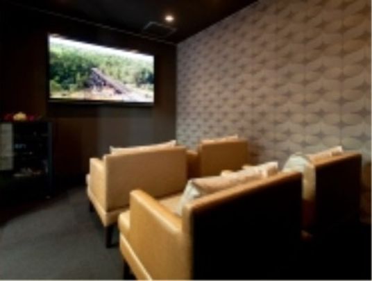 室内には大画面のスクリーンが設置されており、映像が映し出されている。スクリーンの前にはソファが設けられている。