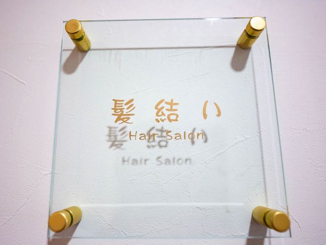看板のクローズアップ 看板 明るいデザインの理美容室入口です。身だしなみを整えて、日々をより快適にお過ごしいただけます。
