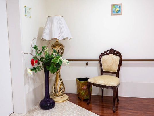 部屋の入り口脇に、デザイン性が高いスタンドライトや、背の高い花瓶、洋風の椅子などが置かれている。小さな絵も飾られている。
