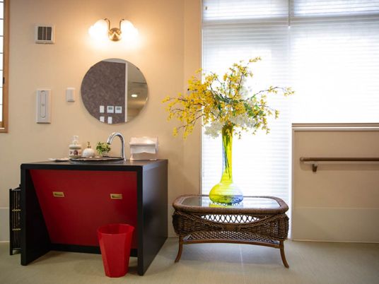 共用の手洗い場の横に、籐でできたテーブルがある。その上に、透明な色付きガラスの背の高い花瓶に花が生けられている。