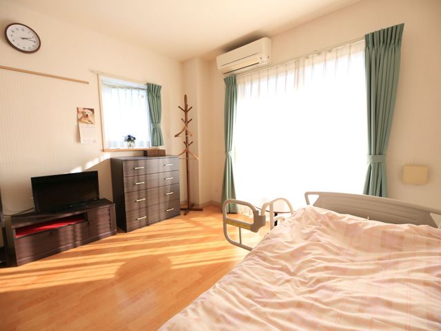 暖かみのある居室 居室 採光が豊かな居室には、必要な家具が揃い、生活しやすい環境が整っています。ベッドのそばにはサポート用の手すりも設置されており、安心して過ごせます。