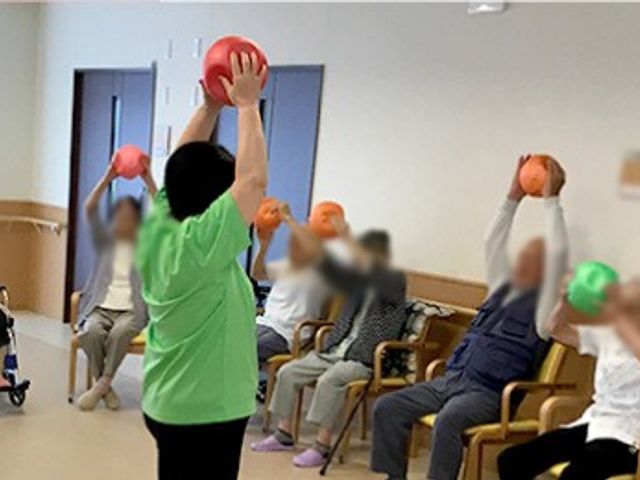 運動する集団の室内 機能訓練室 広々とした空間で、参加者がリラックスして体操を行っています。自然光が心地良く差し込みます。