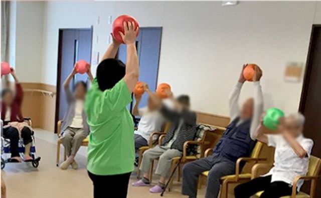 運動する集団の室内 機能訓練室 広々とした空間で、参加者がリラックスして体操を行っています。自然光が心地良く差し込みます。