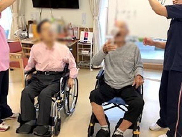 リハビリ支援の様子 機能訓練室 車椅子を利用した方々が和やかにリハビリを受けている光景です。スタッフのサポートがあります。