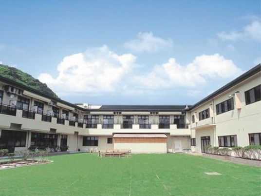 緑色のグラウンドを囲むように建てられている。薄いベージュの外壁と淡い紺色の屋根である。ベランダが付いている。