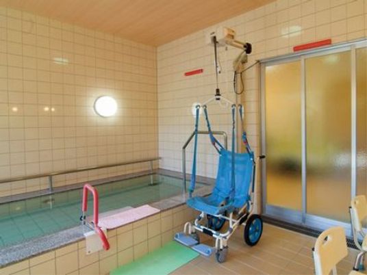 壁や床、天井は、黄色のタイル貼りである。浴槽には手すりが付いており、介護用のリフトも設置されている。