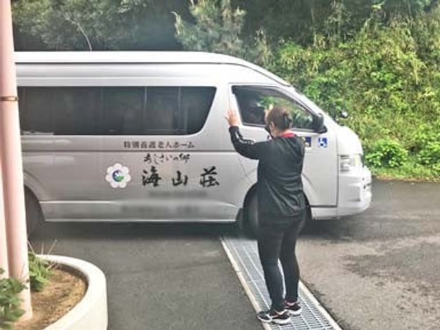 車を見送るスタッフ 外観 スタッフが利用者の車を見送っています。温かい見送りが日常を支えています。