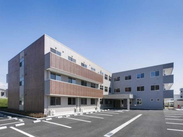 清潔感ある施設の外観 外観 整った駐車場を有する快適な建物です。明るく開放的な空間が、ご利用者様の快適な日々をサポートいたします。