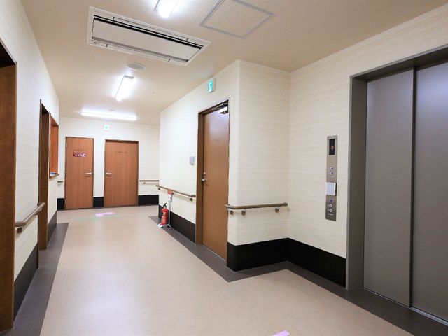 清潔な施設の廊下 エレベーターホール ゆったりとした通路は清潔感があり、手すりも完備しており安心してご利用いただけます。エレベーターへのアクセスも良好で、移動がスムーズです。