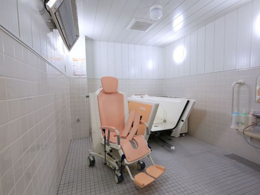 広々とした空間に介護浴槽が置かれている。壁はタイル張りになっており、洗い場にはシャンプー類が用意されている。