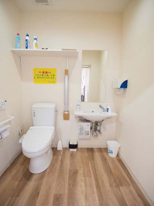 手洗い場が備えつけられている共用トイレである。温水洗浄機能付きで、上部の棚には洗剤などが置かれている。