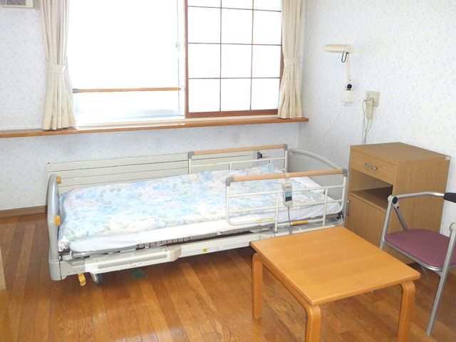 居室のシンプルな空間 居室 自然光が差し込む、暖かい雰囲気の居室です。テーブルや椅子があり、くつろぎやすい環境になっています。
