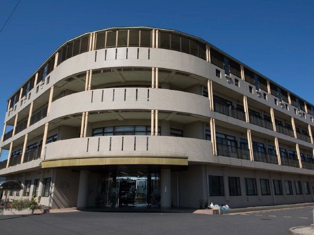 施設外観 外観   曲線を描くバルコニーが印象的な建物です。明るい空の下で、落ち着いた雰囲気が感じられます。