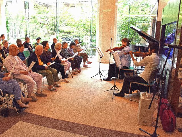 音楽演奏のイベント イベント ゆったりとした椅子に座る方々が、生のバイオリン演奏を聴きながら、心地よい時間を過ごされています。公演や催事に対応する充実した施設で、ご自身のスキルを活かせるやりがいを感じていただけるでしょう。