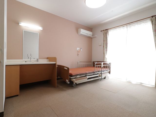 居室のベッドと洗面台 居室 広々とした窓で明るく、快適な個室です。必要な設備が整い、穏やかな時間を過ごせます。