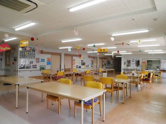 広々とした明るい食堂 食堂1 掲示物で彩られた、活気ある食堂の風景です。ゆったり配置されたテーブルと椅子が、共に時間を過ごす場を提供しています。