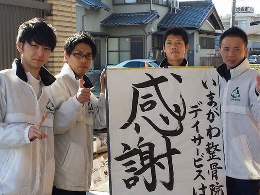 スタッフが看板を持つ外観  