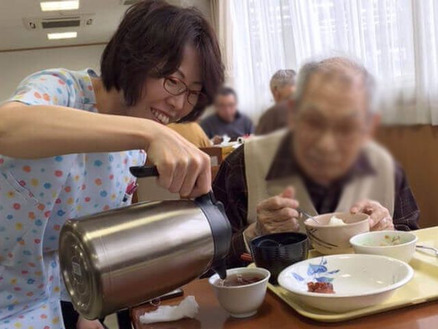 温かい食事の場面 ダイニングルーム スタッフが温かくサポートする、ゆったりとした食事のひとときです。利用者様の笑顔が見られます。
