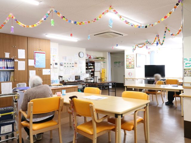 広い共有スペースの様子 多目的スペース。 明るく広々とした食堂では、装飾が施され、居心地の良い雰囲気で皆様がくつろいでいます。利用者の方々が集い、交流を深めることができる空間となっています。