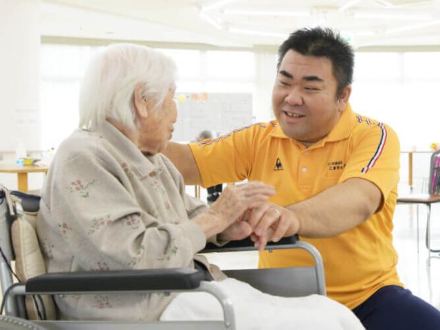 明るい交流の場 ラウンジ 広々とした明るい場で、入居者が職員と笑顔で交流している様子です。安心感があります。