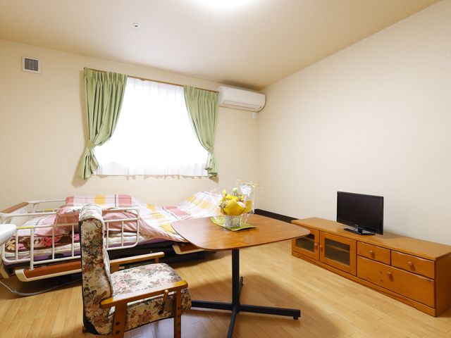 居室と窓の明るさ 居室 ゆったりしたベッドと明るい窓が特徴の居室です。テーブルとテレビが配置され、快適な日常生活を支援します。