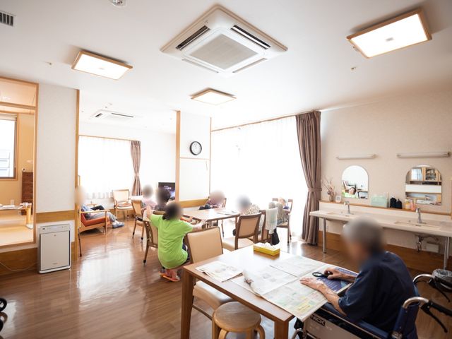 共有スペースでくつろぐ人々 共有スペース ゆったりとした明るいラウンジで、居住者が日々のひとときを過ごしています。共同スペースでのコミュニケーションが豊かな就業環境を形成しています。