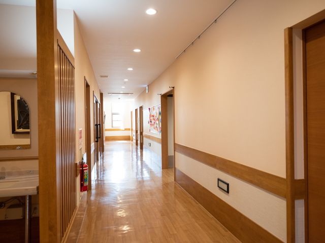 木目調の温もりある廊下 通路 落ち着いた雰囲気の廊下が続く職場です。手すり完備で安全に歩行できる設計となっています。
