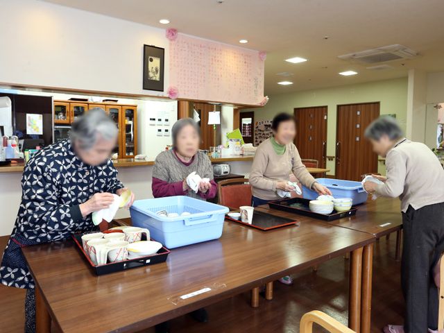 居室での活動風景 キッチン 明るく清潔感のある食堂で、利用者が楽しみながら食事の準備を手伝っています。お互いの協力を通じて、コミュニケーションも育まれることでしょう。